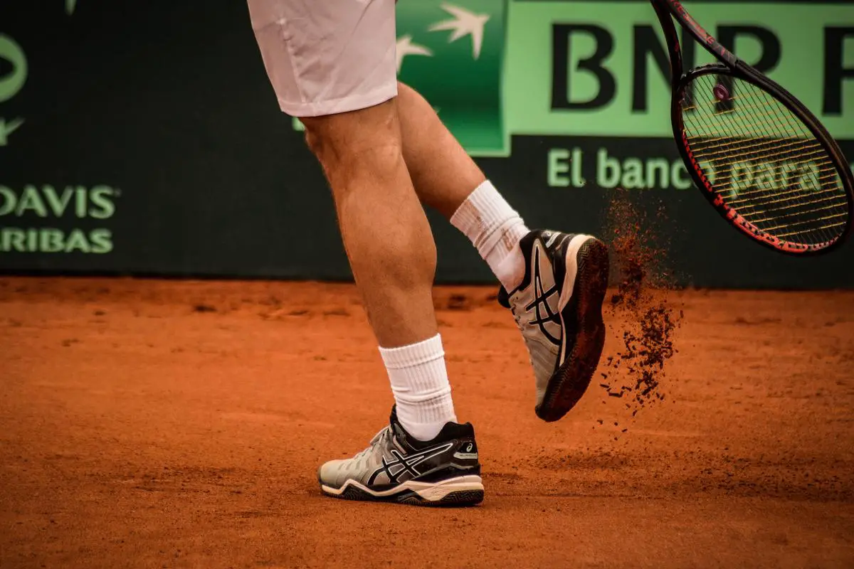 Tennis player hitting a ball with a racket on a clay court