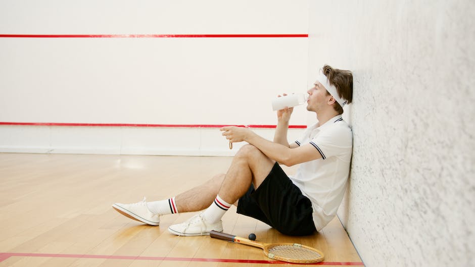 A picture showing a tennis player drinking water from a bottle during a match.