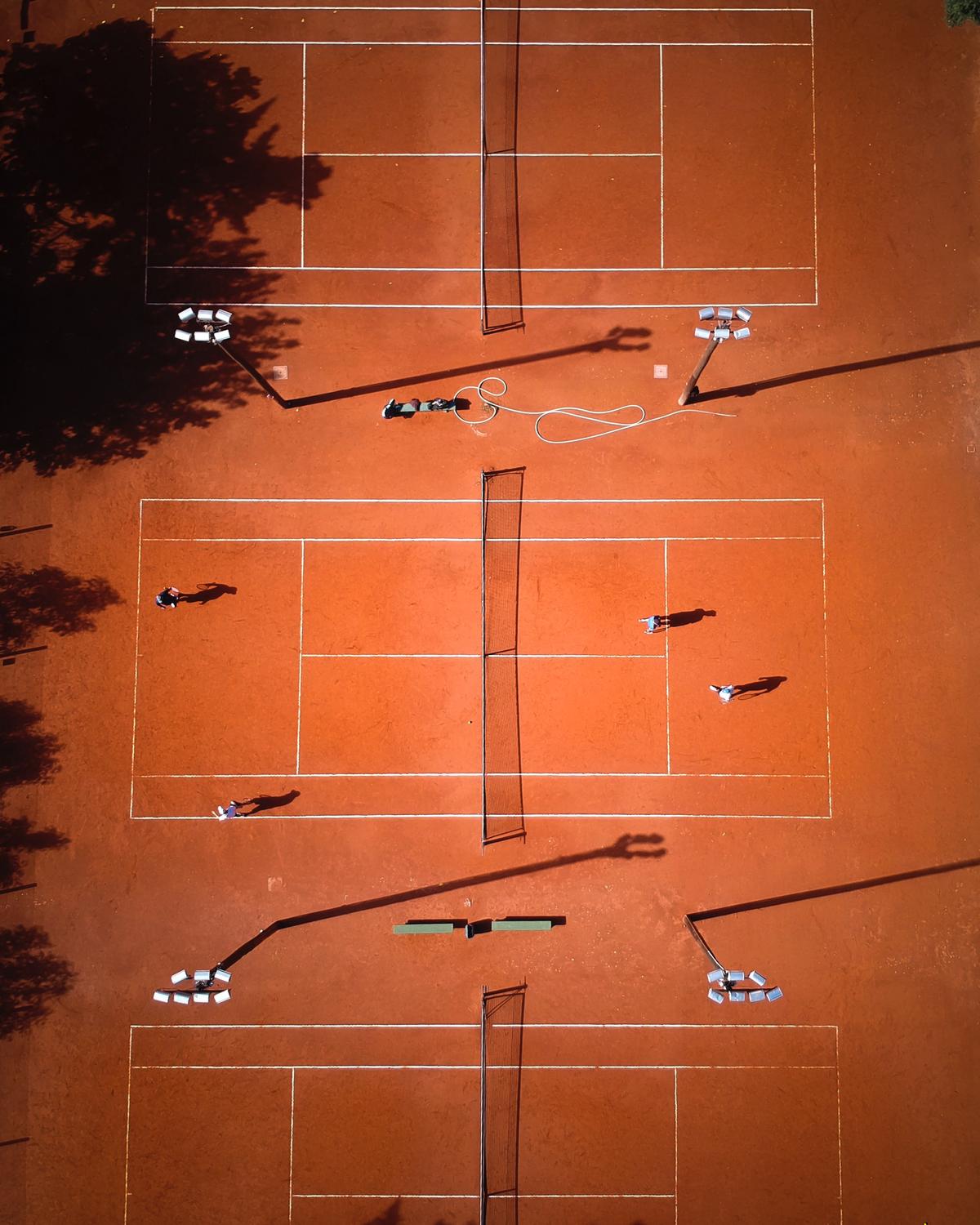 A group of people playing Padel Tennis on an enclosed court with walls, showcasing the dynamic and strategic gameplay.