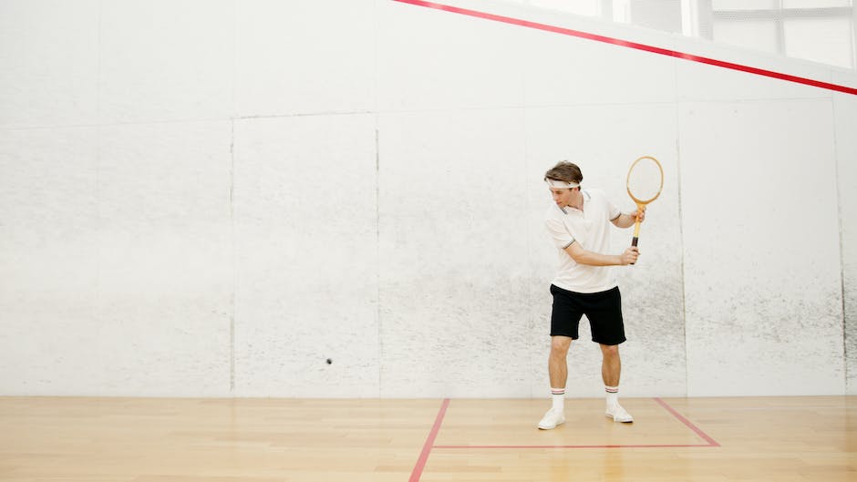 An image showing a person playing squash on a squash court.