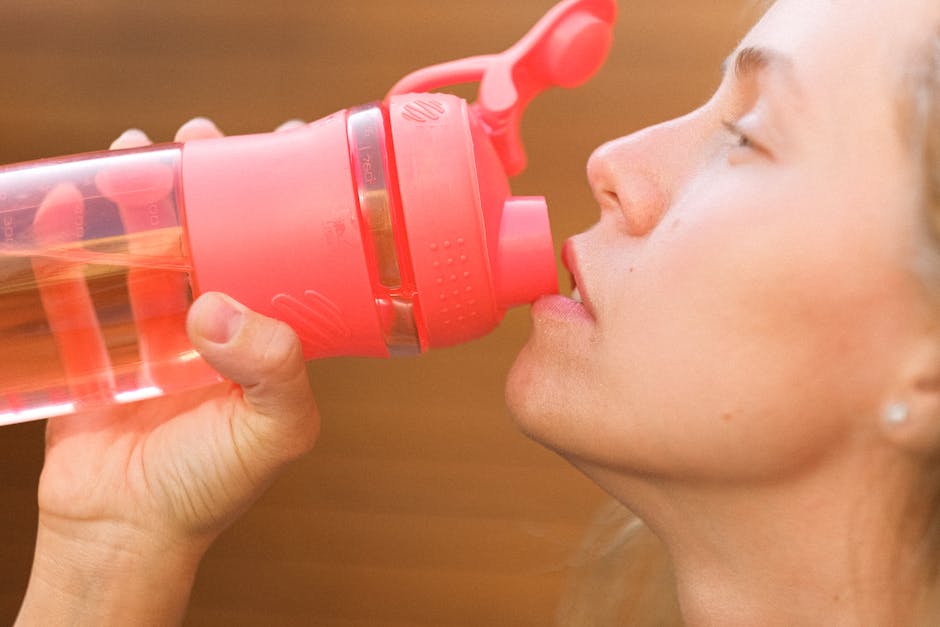 A female tennis player holding a water bottle and eating a healthy snack, demonstrating good nutrition practices for optimal performance.