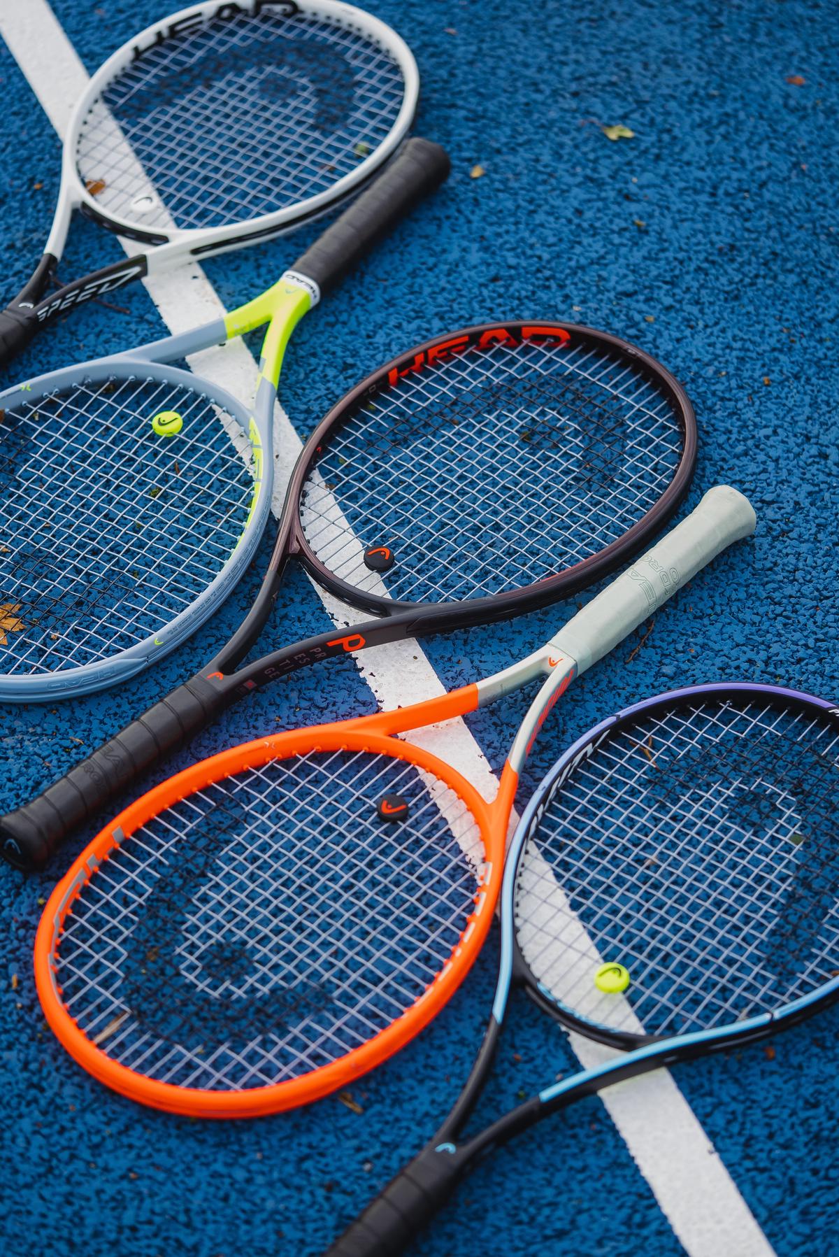 A set of four tennis rackets on a tennis court with the green background blurred out