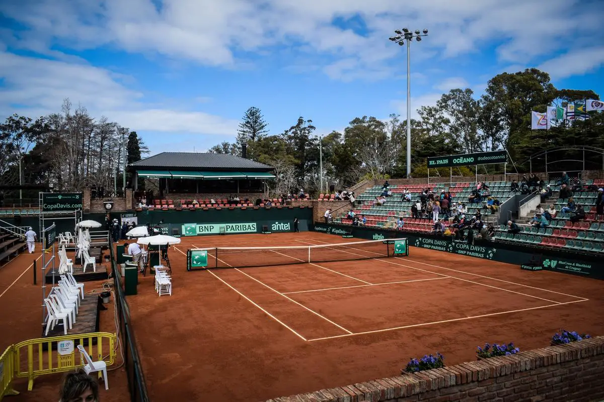 An image of a tennis player on the court surrounded by tennis sponsor logos.